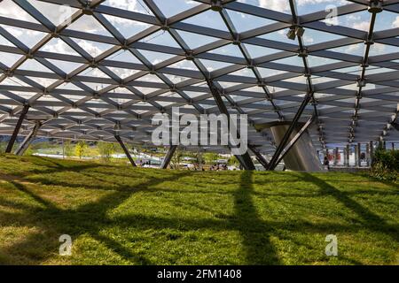 Glass roof with oval metal partitions. Shadow from the base on the grass. Stock Photo