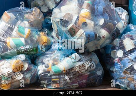 London, UK, 30 April 2021: a mound of blue plastic bags containing single-use coffee cups wait to be collected for recycling on Tooley Street, beside Stock Photo