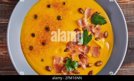 Panoramic view traditional pumpkin puree cream soup with carrots, onions, ginger, garlic, coconut milk. Added seeds, fried bacon, parsley. Healthy, vegetarian food Stock Photo