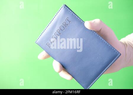 hand in blue surgical gloves holding passport in hand. Stock Photo