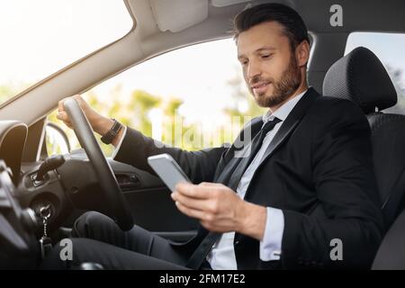 Handsome businessman driving car, using mobile phone Stock Photo