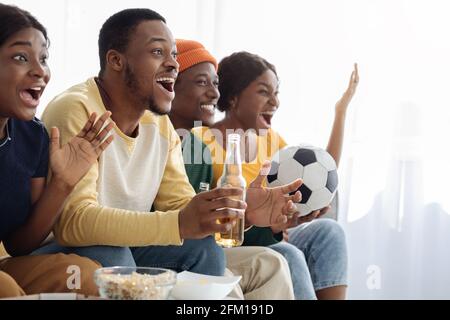 Excited black friends football fans watching game at home Stock Photo