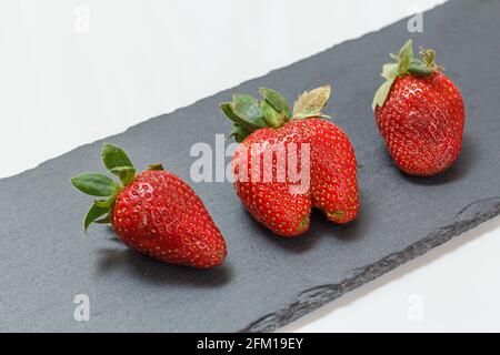 Red ripe strawberries on a black stone cutting board Stock Photo