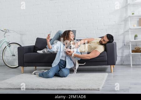 smiling young woman taking selfie with jack russell terrier and muslim boyfriend Stock Photo