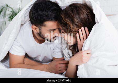 interracial couple with closed eyes lying under blanket Stock Photo