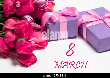 Tulips and lilac gift boxes with an inscription 8 March. International women's day greeting card on white background Stock Photo