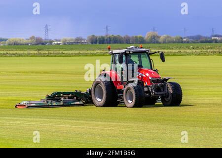 Tarleton UK Weather 5th May 2021; Bright sunny start to the day for commerical turf growers in Lancashire mowing grassland with the award winning Massey Ferguson farm tractor 5713;   Sod is typically used for lawns, golf courses, and new housing around the world. In residential construction, it is sold to landscapers, home builders or home owners who use it to establish a lawn quickly and avoid soil erosion. Credit MediaWorldImages/AlamyLiveNews Stock Photo