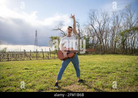 Young musician with a guitar in his hand waves his arm. Stock Photo