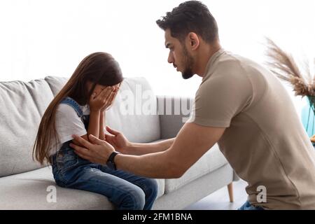 Little girl crying, upset young father consoling daughter Stock Photo