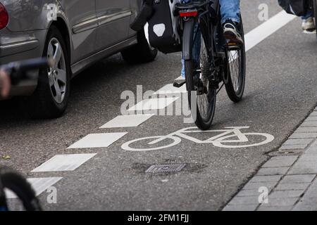 Freiburg, Germany. 05th May, 2021. A cyclist rides on a bicycle safety lane while being overtaken by a car. The cross-state campaign 'sicher.mobil.leben' (safe.mobile.living) is focusing on cycling safety this year. Credit: Philipp von Ditfurth/dpa/Alamy Live News Stock Photo