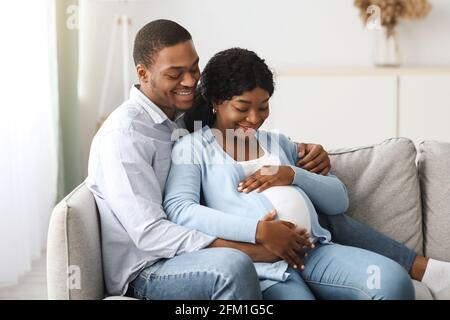 Loving pregnant couple enjoying time together at home Stock Photo