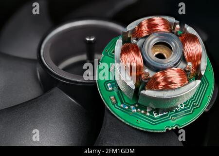Closeup of inductors on stator, permanent magnet in rotor and black blades on background. Electric EC motor of open computer fan. Green circuit board. Stock Photo