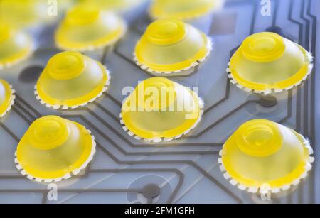 Electronic flexible printed circuit in detail of computer keyboard silicone membrane. round yellow dome switches of push buttons on gray plastic sheet. Stock Photo