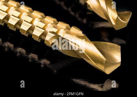 CLose-up of sharp titanium coated drill bits tips in artistic still life. Gold steel tools with serrations for horizontally drilling after making hole. Stock Photo