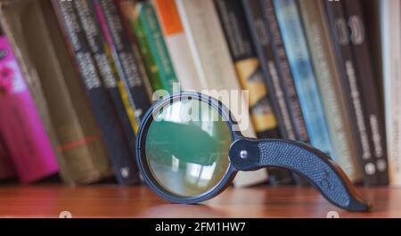 Magnifying glass on a bookshelf, background with books Stock Photo