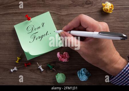 Don't forget on sticky note man hand writing on wood table Stock Photo
