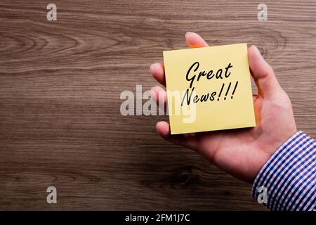 Conceptual hand writing showing Great News.Hand holding sticky Note Paper Stock Photo