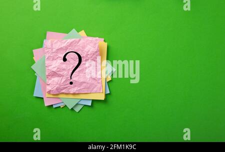 Question mark drawn on notepad. Over green background with copy space. Stock Photo