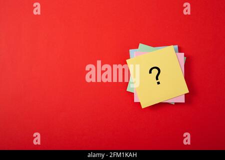 Question mark drawn on notepad. Over red background with copy space. Stock Photo