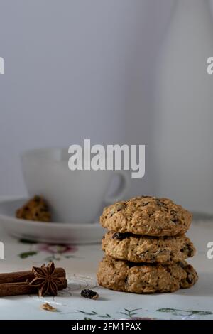 Chocolate Chip and Oatmeal Cookies in white plate on wooden background and decorated with spices flower- served with emtpy teacup Stock Photo