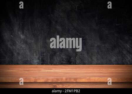 Wooden table with black wall as template. Empty brown tabletop and chalkboard, space for text, objects Stock Photo