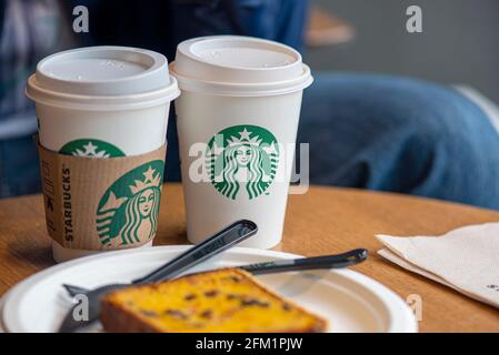 BERLIN - MAY 02: White paper cup with modern Starbucks logotype on a table at the Starbucks cafe in Berlin, May 02. 2021 in Germany Stock Photo
