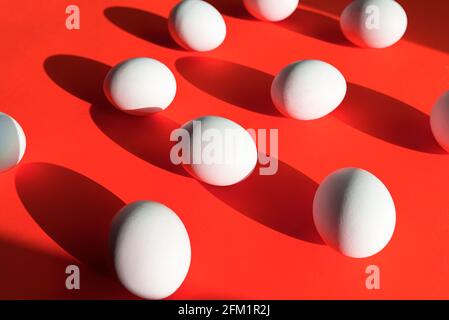 Many eggs on red surface, creativity picture with white  chicken egg, abstract composition with light and shadows Stock Photo