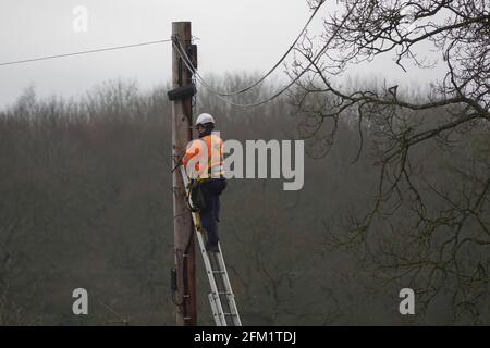 British Telecom Openreach engineer working at height at the top of a telegraph pole in the countryside Stock Photo