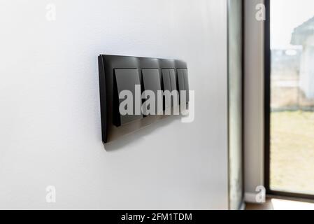 Black frame with a button to switch the lights and roller shutter up and down on the gray wall of the house. Stock Photo