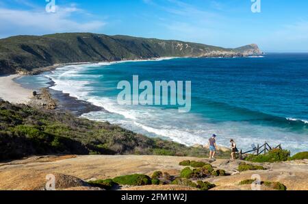 Couple standing on granite rock overlooking Cable Beach Torndirrup peninsula Torndirrup National Park Albany Western Australia. Stock Photo
