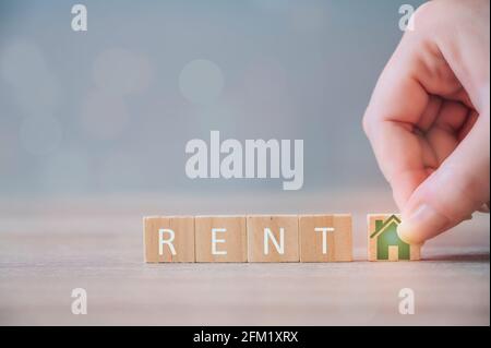 Property investment and house mortgage financial concept. Hand holding wood cubes blocks with house icon and word RENT. Property investment and house Stock Photo