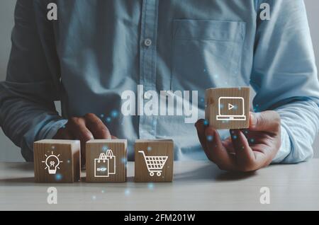 Shopping online business concept. Man hand holding a wooden cube with a icon shopping.Marketing online Business. Stock Photo