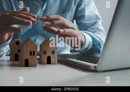 Real estate insurance concept business. businessman hand on house and computer laptop.Property  security concept. Stock Photo