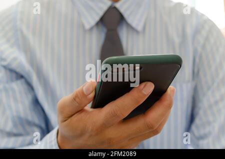 Close up hand holding businessman using mobile smart phone communicate online browse internet. Stock Photo