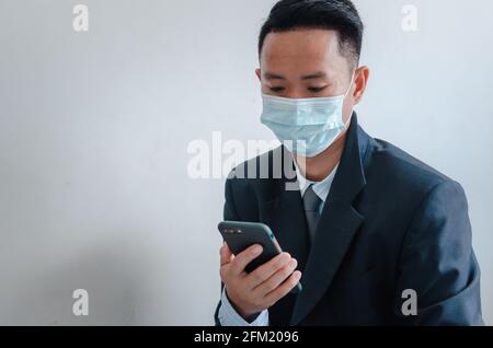 Business men wear face masks to watch mobile phones. Stock Photo