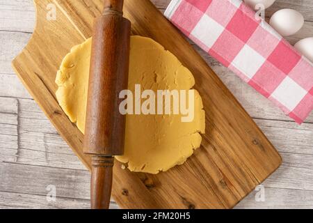 rolled out cake dough on a wooden board with rolling pin Stock Photo