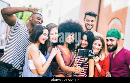 Multiracial friends taking video selfie with mobile phone on stabilized gimbal - Young people having fun on new tech trends Stock Photo