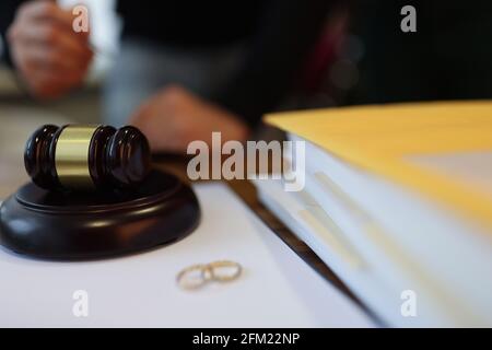 Wedding rings and wooden judge gavel lie on table Stock Photo