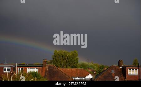 Wimbledon, London, UK. 5 May 2021. Afternoon skies darken dramatically as a band of heavy rain sweeps over London, a low rainbow forms as the storm passes. Credit: Malcolm Park/Alamy Live News. Stock Photo