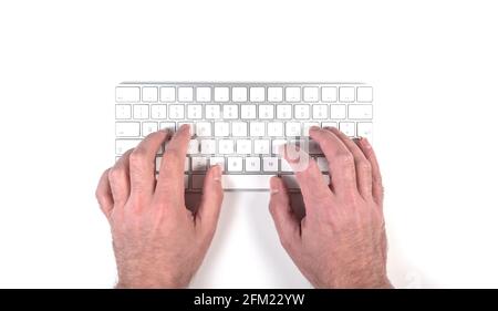 top view of person typing on wireless computer keyboard on white desk Stock Photo