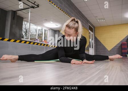 Beautiful young woman doing splits in sport studio Stock Photo