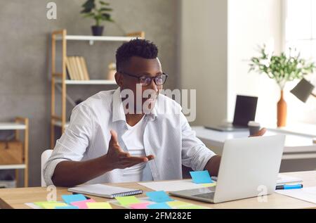 Portrait of young cheerful african american man having video call on laptop Stock Photo