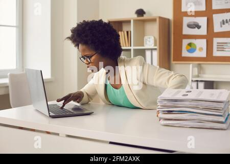 Business woman working with digital files on laptop instead of dealing with paper documents Stock Photo
