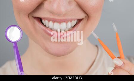 Close-up portrait of a smiling woman holding a brush and a dental mirror Stock Photo