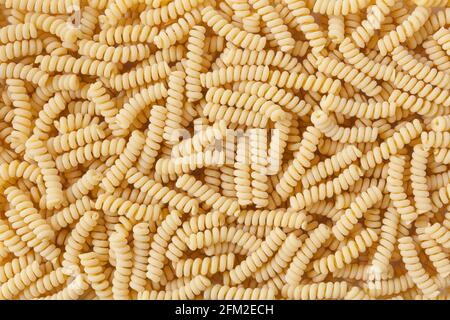 Uncooked fusilli corti bucati pasta background Stock Photo