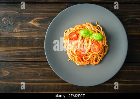 Freshly cooked Spaghetti with tomato sauce and garnished with tomatoes and fresh basil on grey plate Stock Photo Alamy