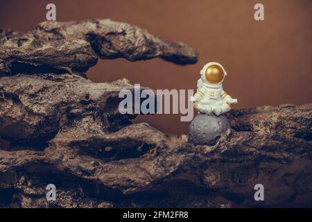 Astronaut wearing white space suit and helmet and meditating while sitting on the moon. Concept of cosmonautics, space travel, freedom, relaxing and p Stock Photo