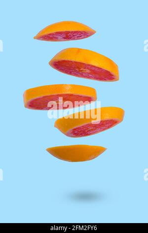 Floating levitating ripe grapefruit on a blue background. Vitamins, healthy diet concept. Minimal fruit idea. Sliced grapefruit floating in the air. C Stock Photo