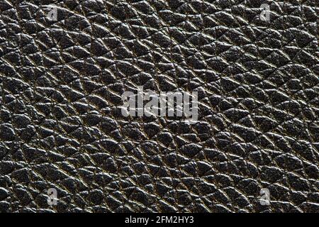 Black with golden highlights artificial leather, dermatin texture macro background pattern for backdrop macro closeup. Stock Photo