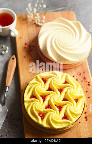 Delicious mini tarts yellow and white with nuts and custard on wooden cutting board. Assortment of delicious and colorful dessert, lemon curd tart, cr Stock Photo